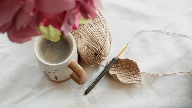 Relaxing scene with coffee, crochet project, and yarn on a table.