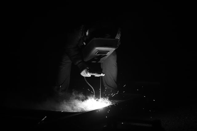 Welder working with sparks flying in a dark setting
