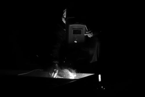 Free A welder skillfully operates in a dark setting, focusing on precision and safety. Stock Photo