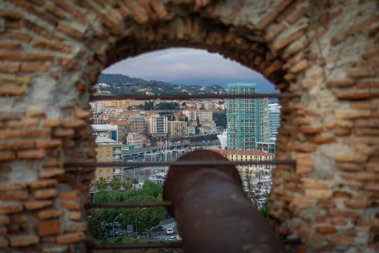 Antique Cannon With A City Harbor In The Background