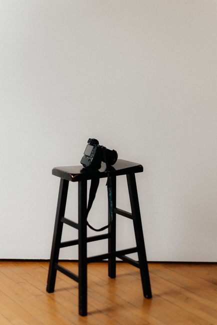 A simple photo studio scene with a camera resting on a wooden stool.