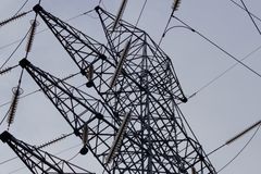 Low angle shot of a metal power transmission tower with cables against a clear sky.