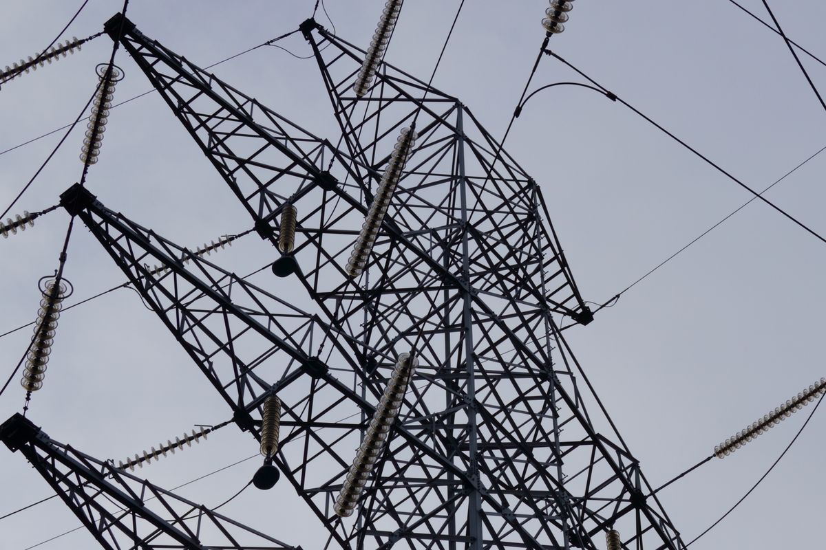 Metal power transmission tower with cables against a clear sky, the kind of facility covered by root-cause mitigation