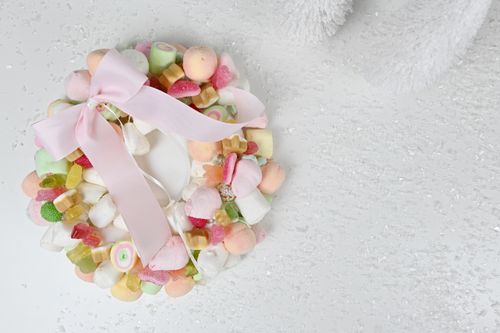 Free A vibrant candy wreath adorned with a pink ribbon on a textured surface, ideal for festive decor inspiration. Stock Photo