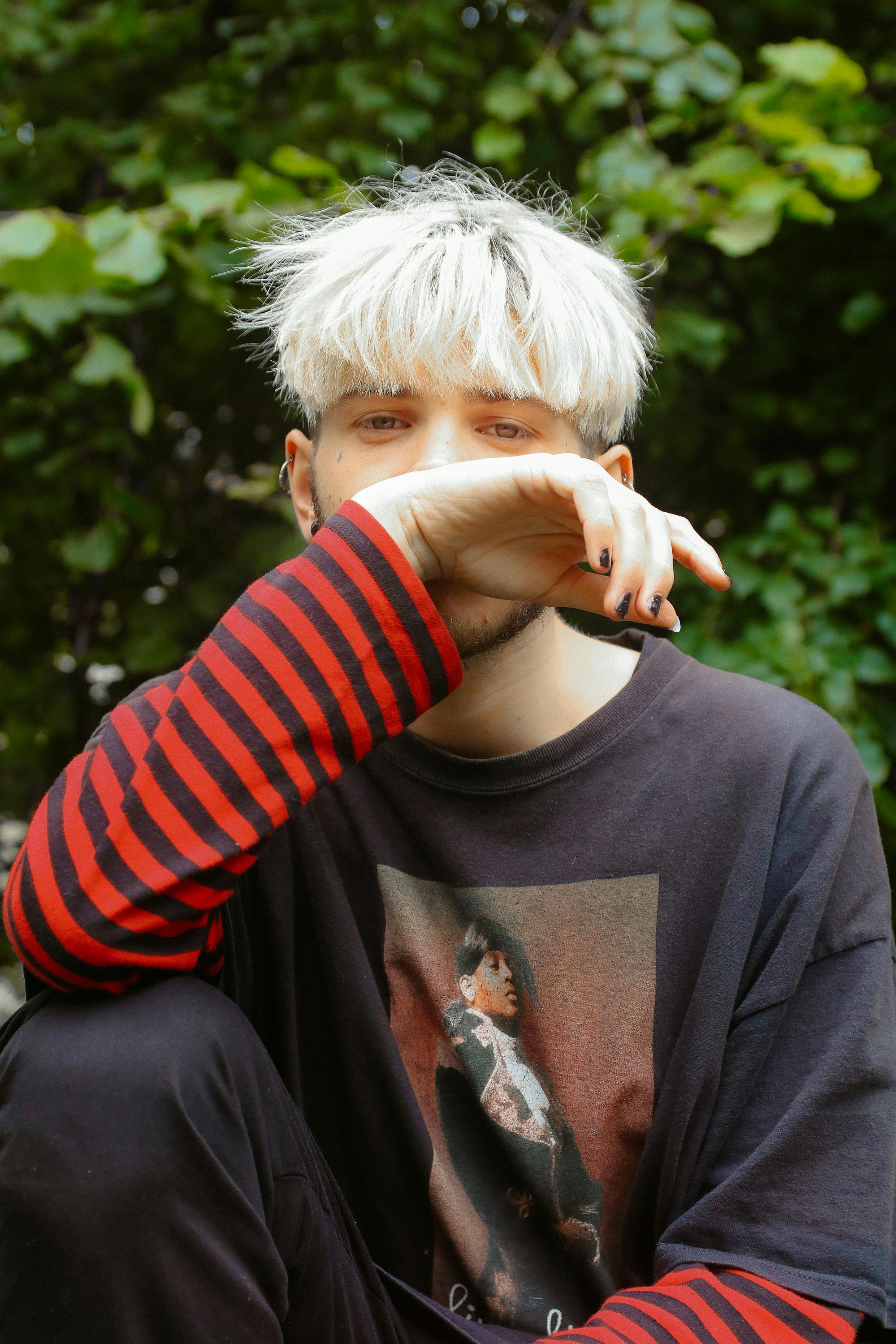 Portrait of a young man with dyed blonde hair sitting outdoors in Wolverhampton.