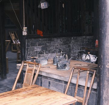 Old-fashioned tea house setup featuring bamboo chairs and aged kettles on a wooden table.