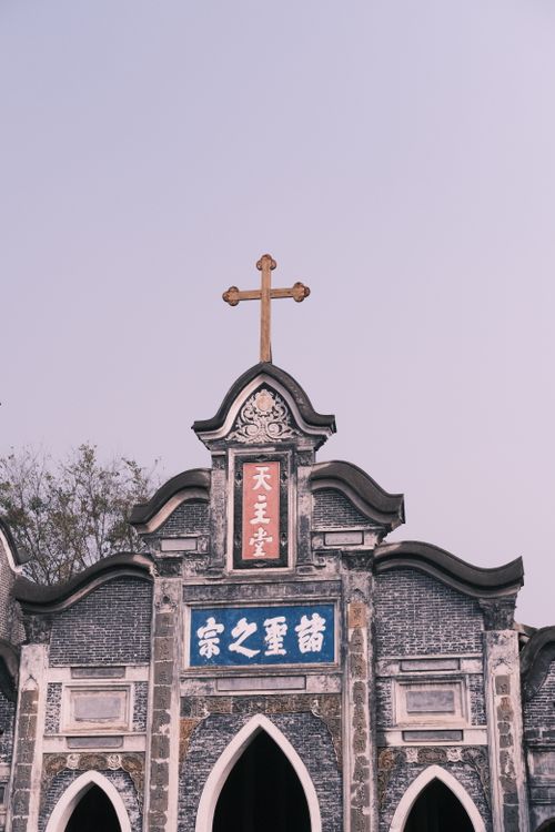 Free Stone facade of a historic church in Vietnam featuring ornate decorations and a prominent cross. Stock Photo