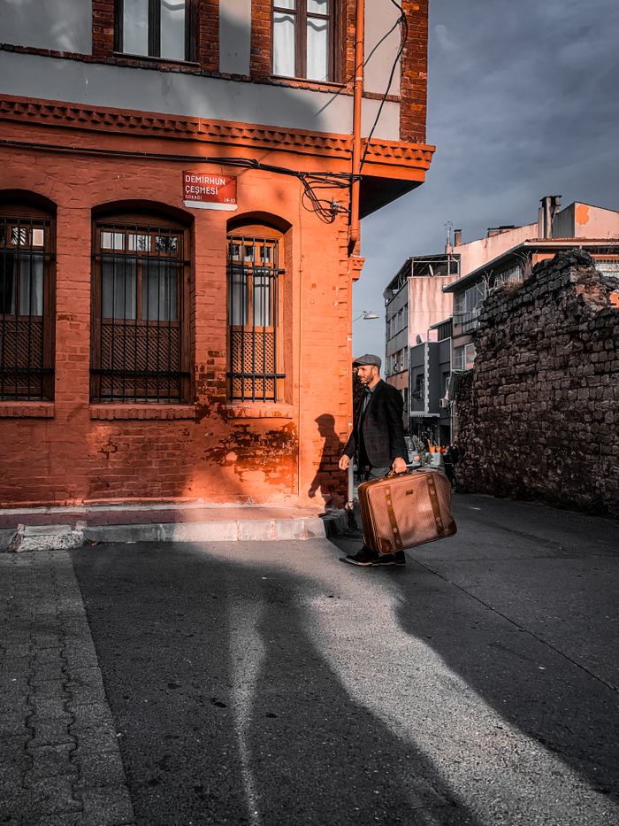 Traveller wheeling a suitcase down a city street — photo by Leo Arslan on Pexels