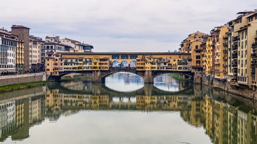 Free A breathtaking view of the iconic Ponte Vecchio bridge reflecting in the Arno River in Florence, Italy. Stock Photo