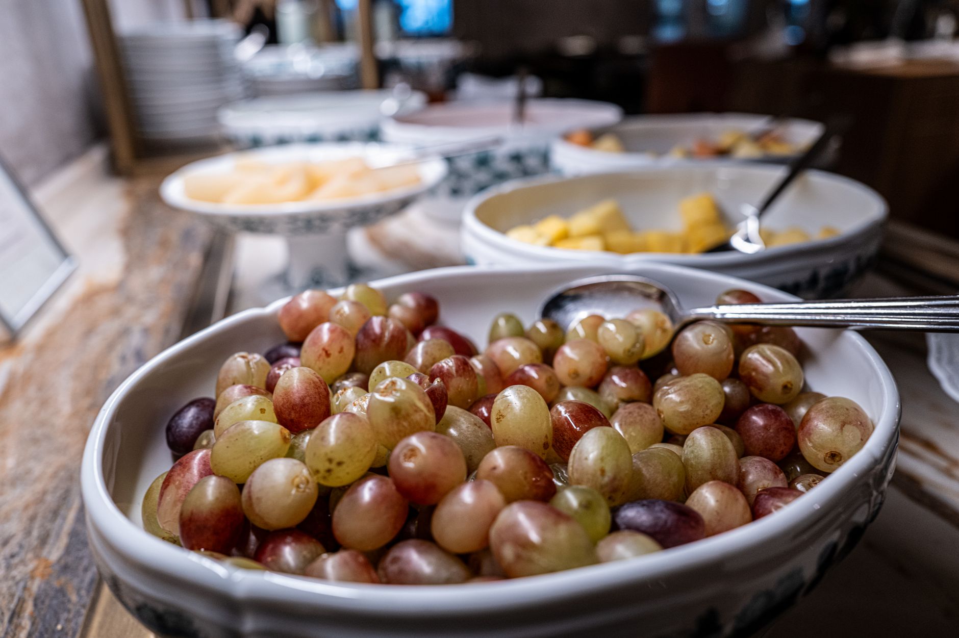 Close-up of fresh grapes in a bowl on a buffet table, highlighting healthy dining options.