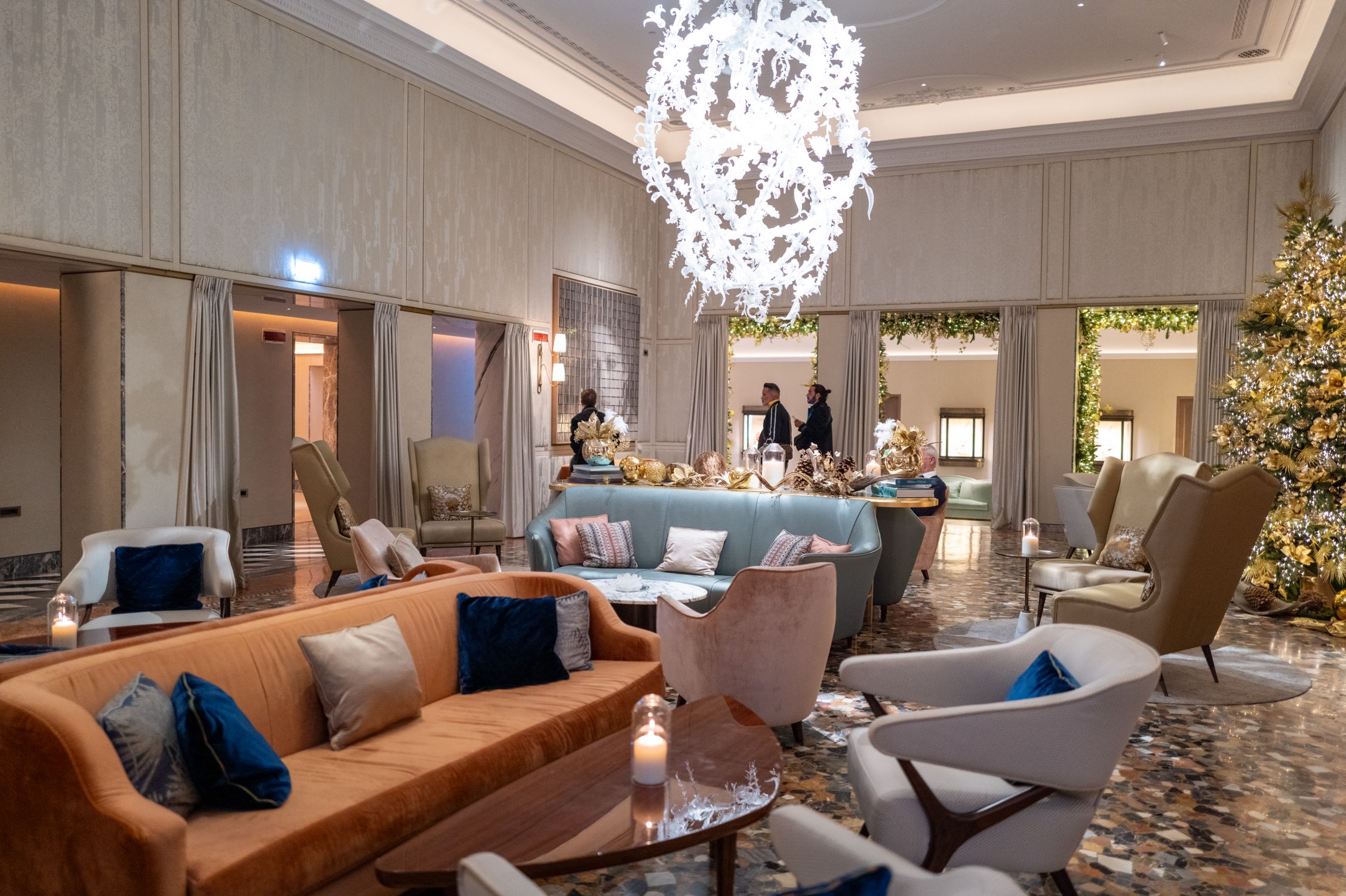 Elegant hotel lobby featuring stylish armchairs, couches, and a grand chandelier.