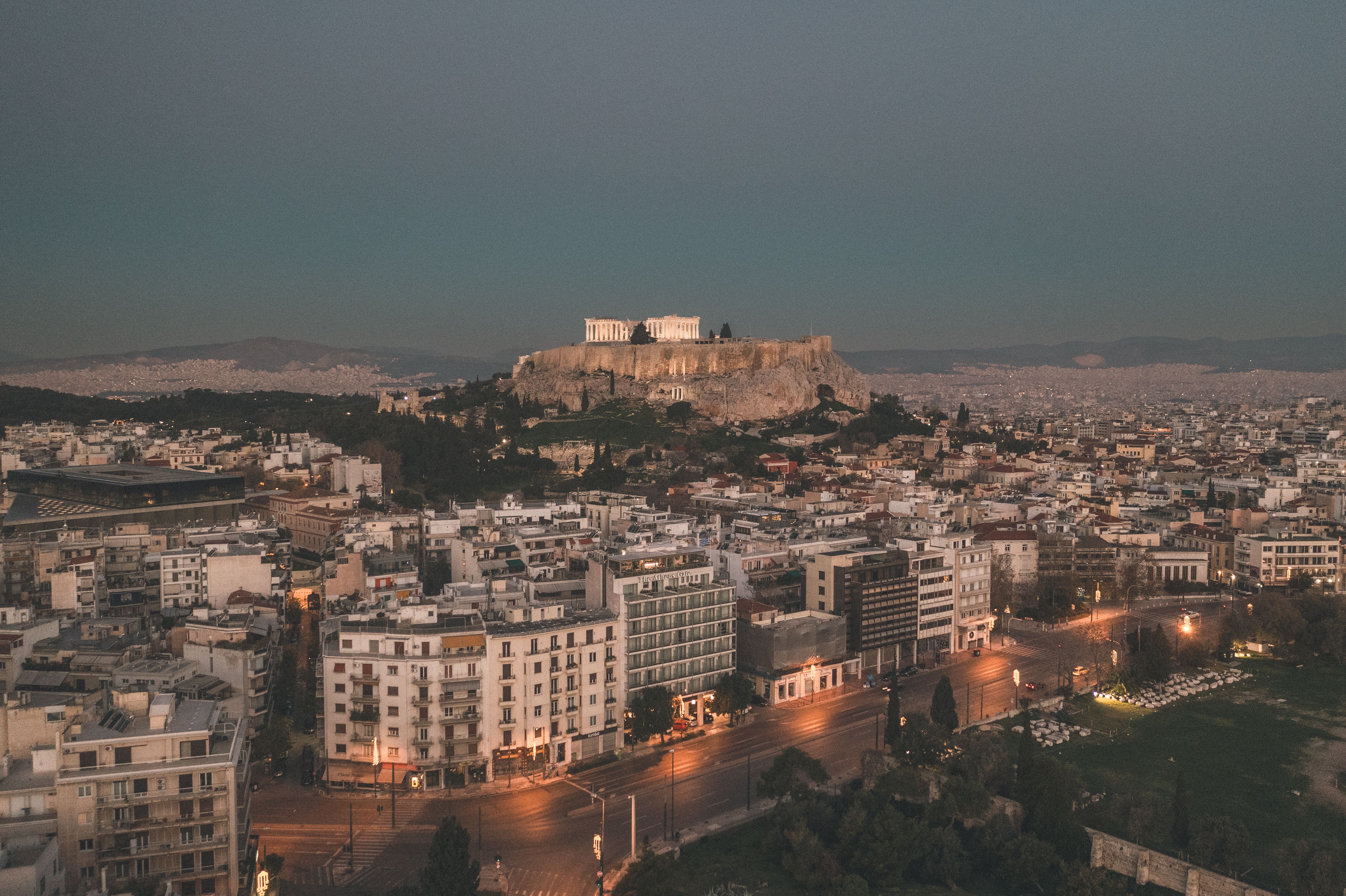 Explore a breathtaking aerial cityscape of Athens, featuring the illuminated Acropolis at twilight. Explore a breathtaking aerial cityscape of Athens, featuring the illuminated Acropolis at twilight.