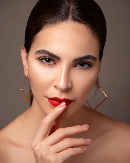 Studio Shot of a Brunette Wearing Red Lipstick and Earrings 