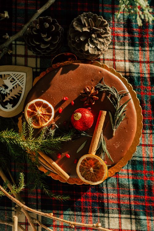 Free A beautifully decorated holiday cake with pine cones, dried oranges, and spices on a plaid tablecloth. Stock Photo