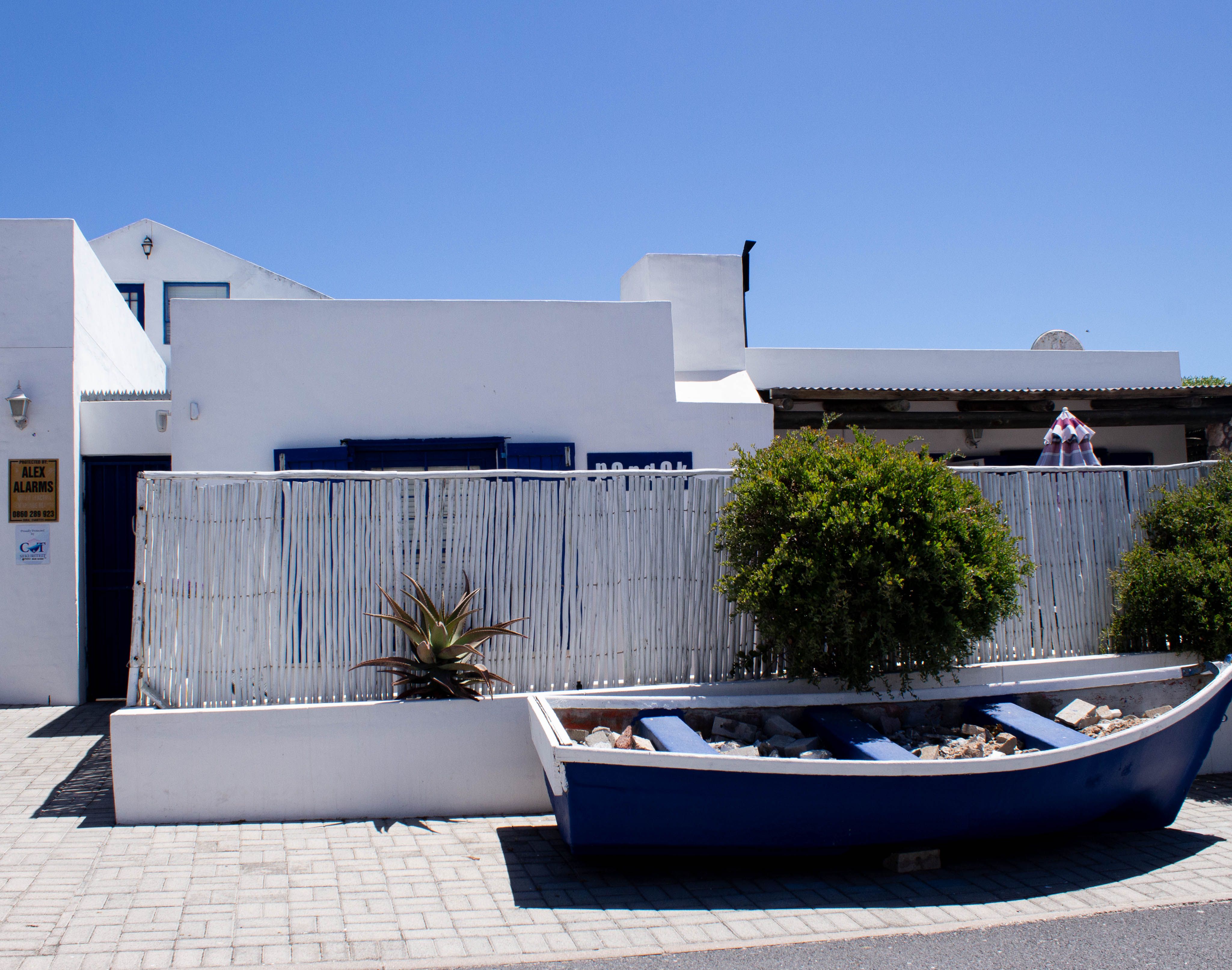 A vibrant coastal house in Paternoster, South Africa, showcasing local architecture and a quaint boat decor.