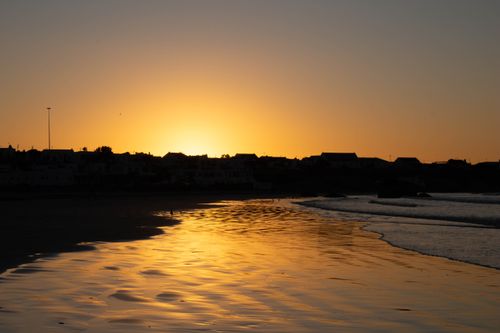 Free Scenic sunset on Paternoster beach with golden reflections creating a serene coastal silhouette. Stock Photo