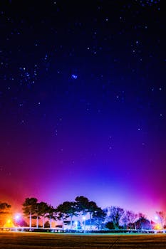 郊区的灯光照亮了前景，让充满活力的星空更显壮丽