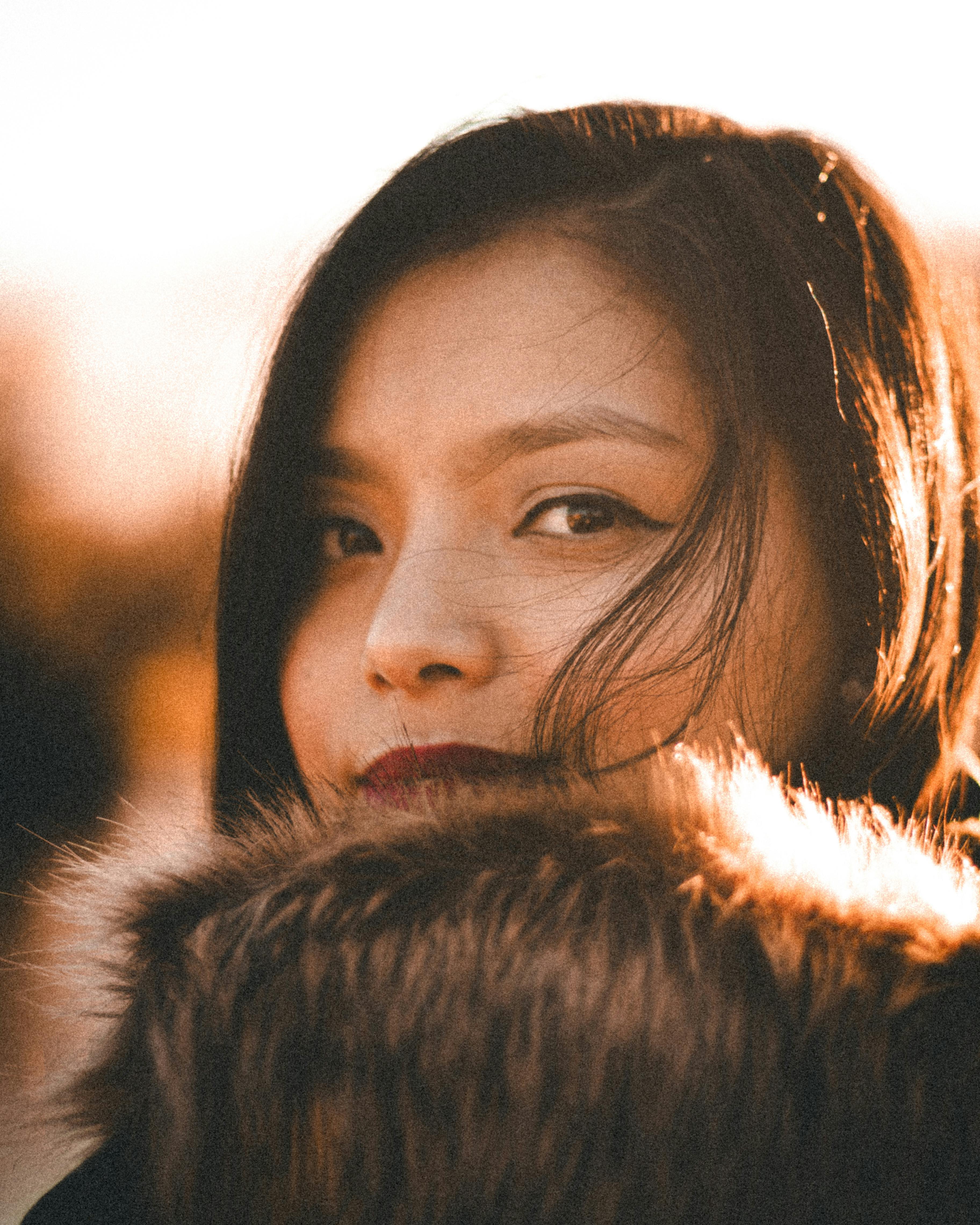 Free Close-up portrait of a woman with fur collar and warm tones, capturing elegance and mystery. Stock Photo