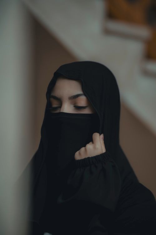 Free Close-up of a woman in a traditional black hijab with eyes closed indoors. Stock Photo