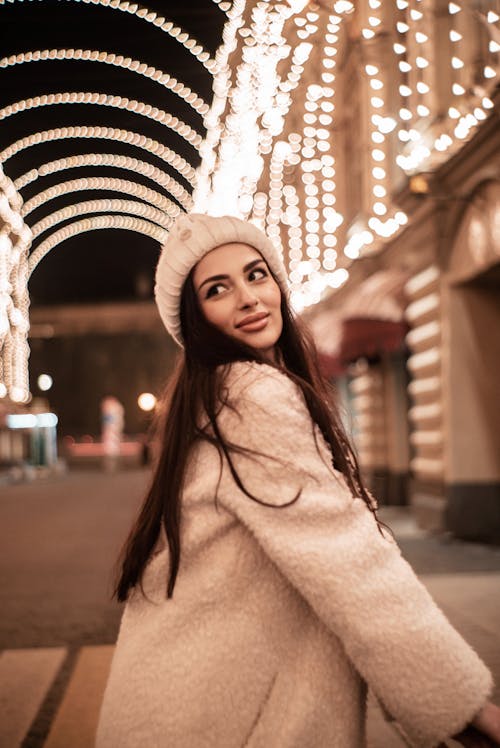 Smiling Brunette Woman in Hat and Coat at Night