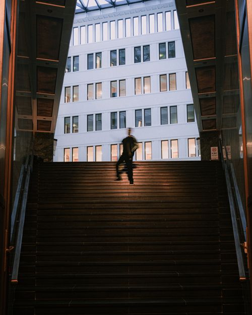 Free A person ascends steps at Potsdamer Platz with modern architecture in Berlin, Germany. Stock Photo