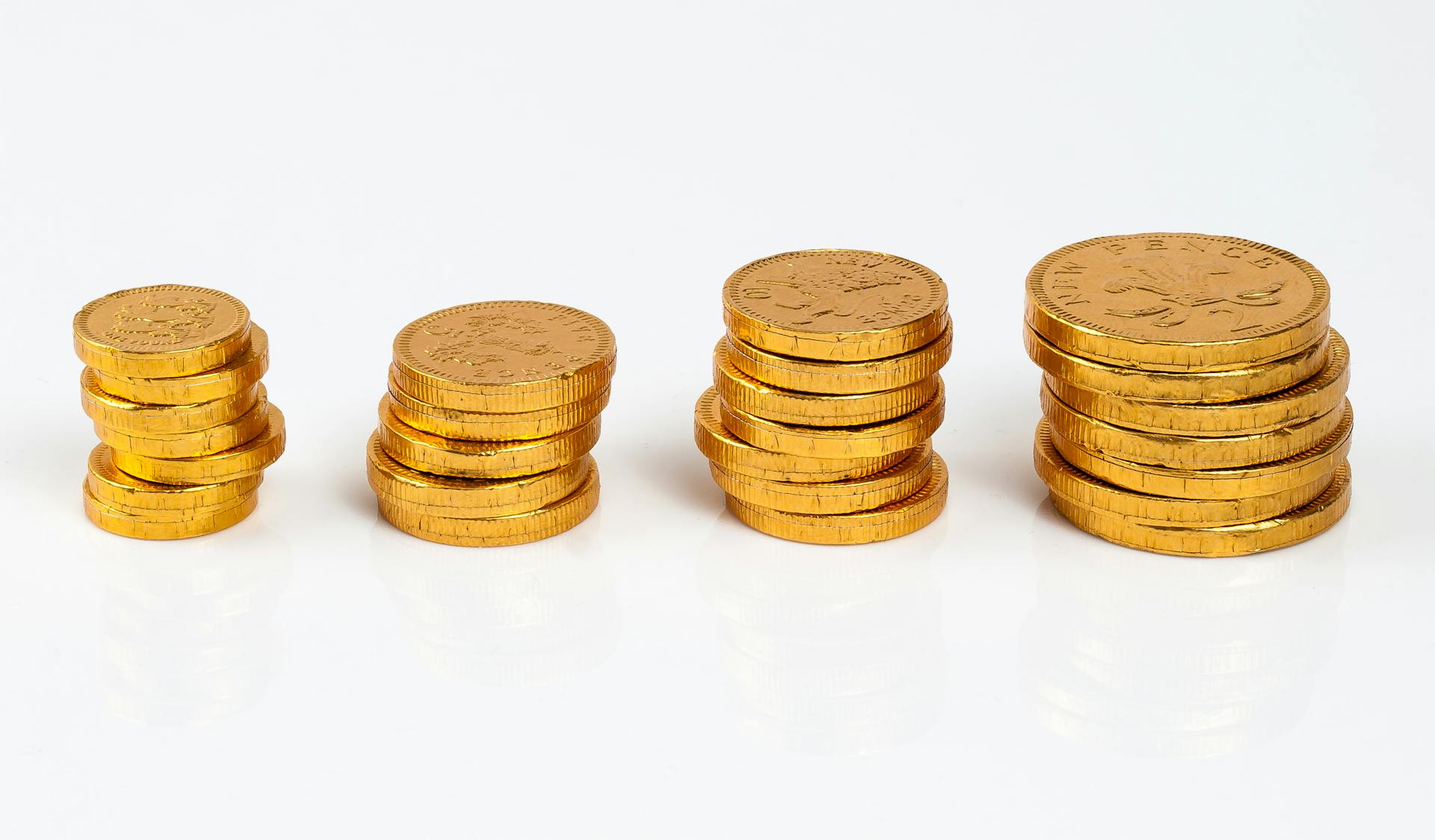 Arrangement of gold coins stacked on a clean white background, symbolizing wealth and abundance.