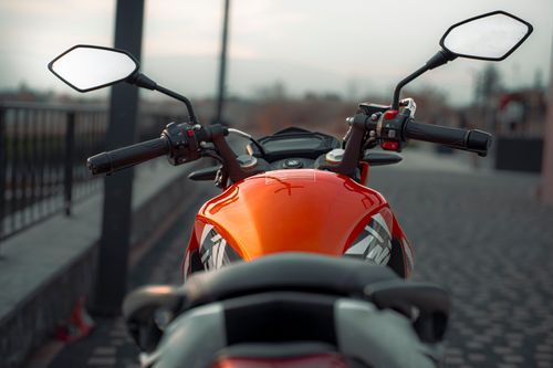 Free Close-up of an orange motorcycle on a city street, showcasing modern design and vibrant colors. Stock Photo