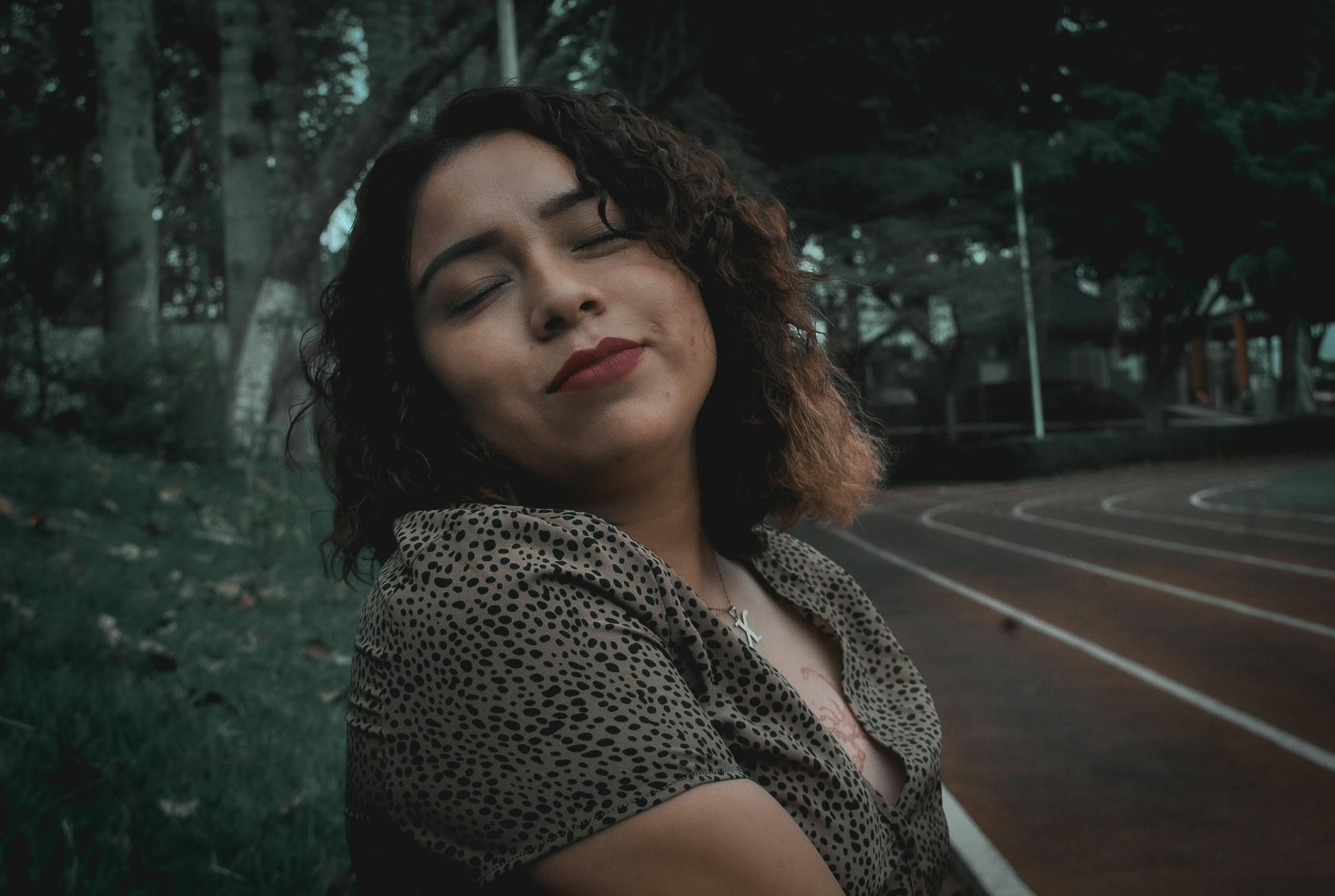 Portrait of a serene woman with curly hair, enjoying autumn in a Huatusco park.