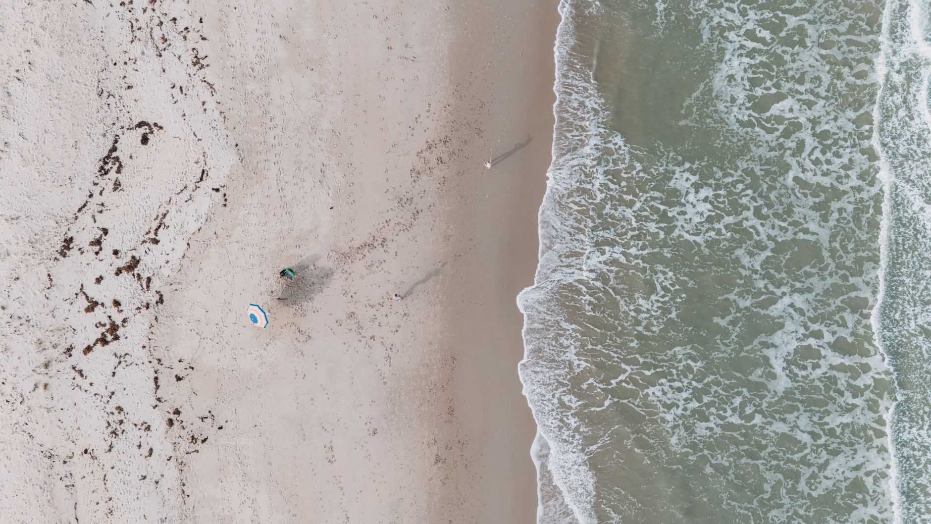 Aerial shot of Fort Pierce beach with gentle waves and sandy shore, showcasing a peaceful coastal scene.