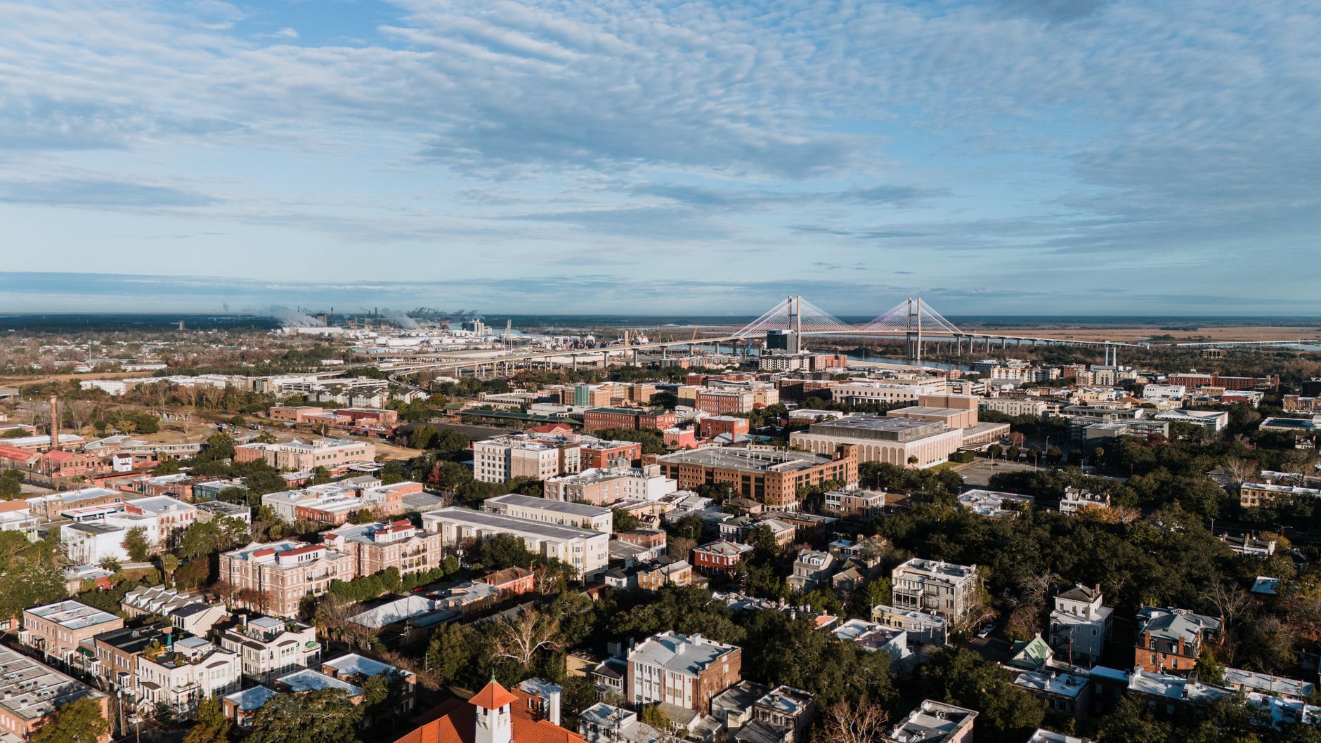 Door hanger delivery in Savannah, GA Door hanger distribution and flyer delivery in Savannah, GA — A sweeping aerial view of Savannah, GA, featuring the Talmadge Bridge and surrounding cityscape. above neighborhoods DoorBlitz crews walk