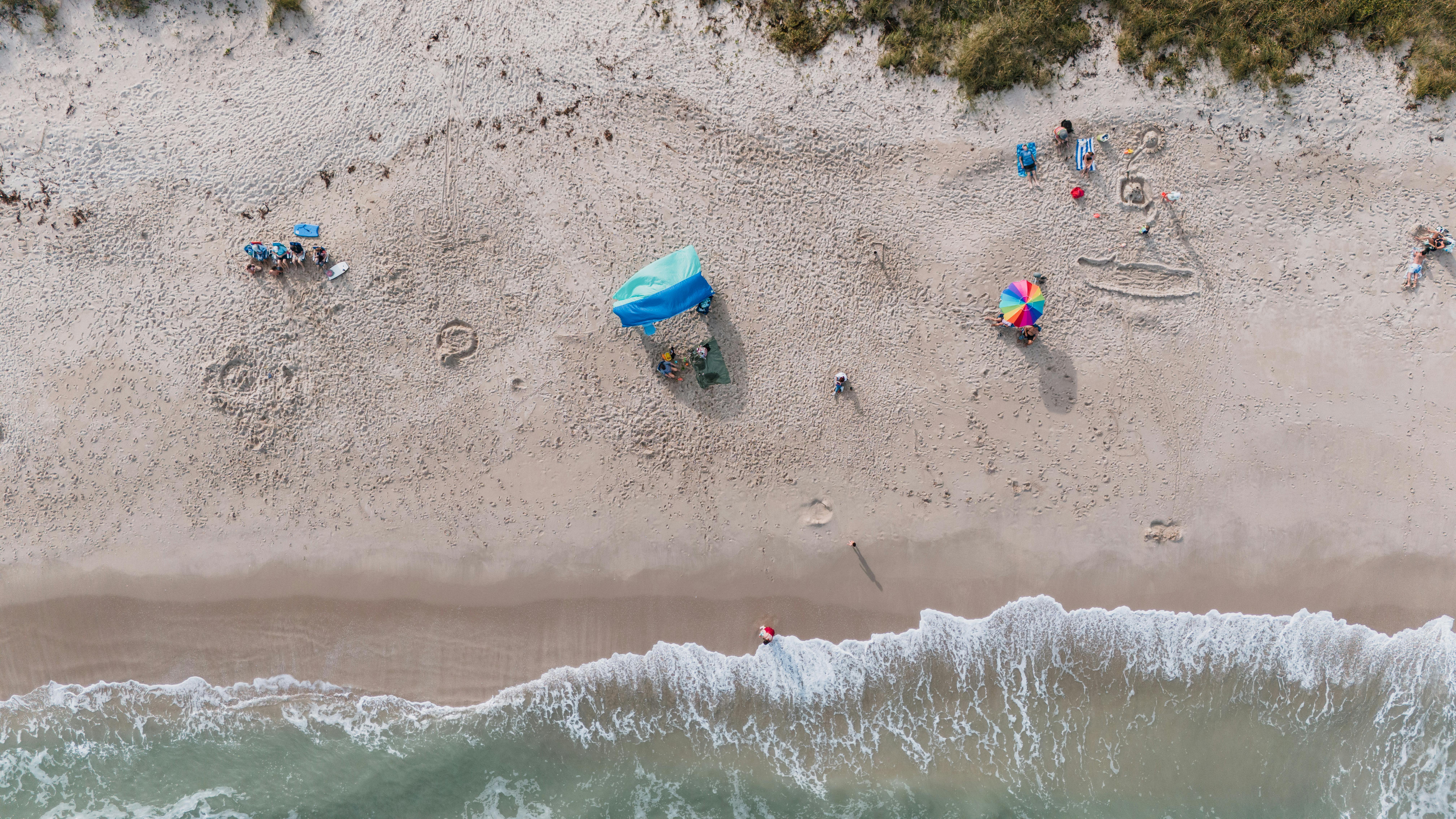 Aerial shot of Fort Pierce beach depicting sand, sea, and beachgoers enjoying a sunny day.