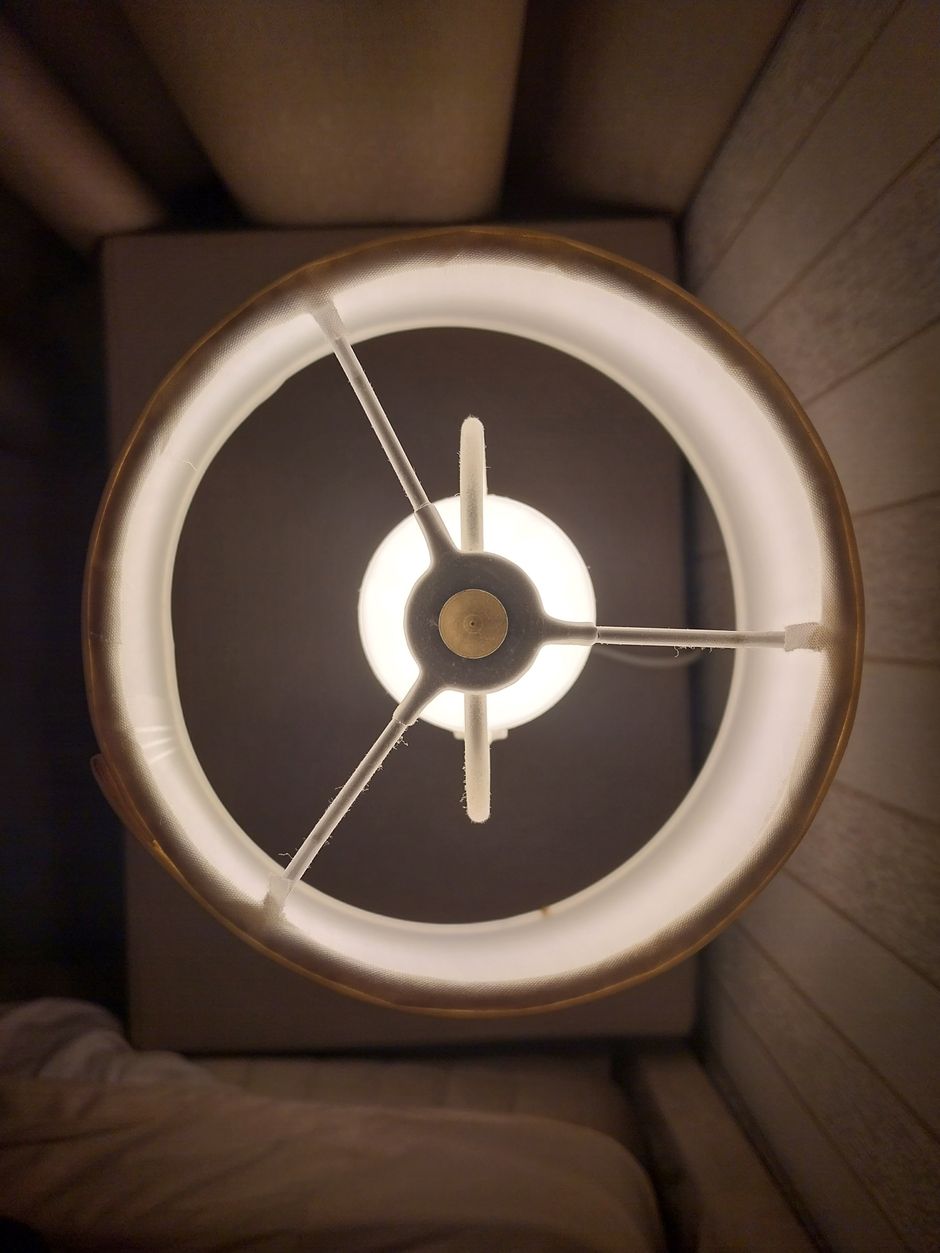 A detailed view of a modern lamp illuminating a cozy bedroom setting.