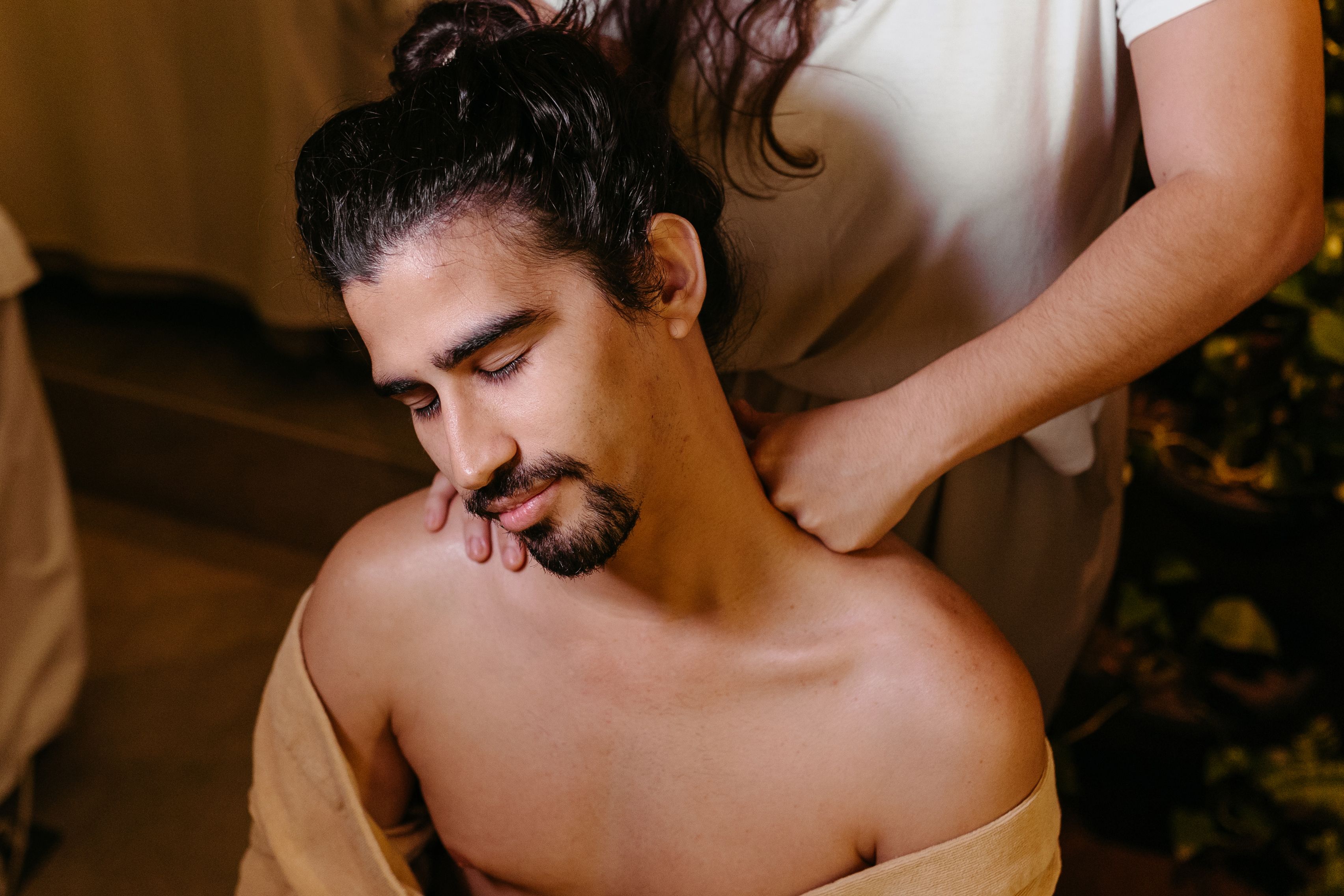 Free A serene spa scene showing a man receiving a therapeutic shoulder massage indoors. Stock Photo