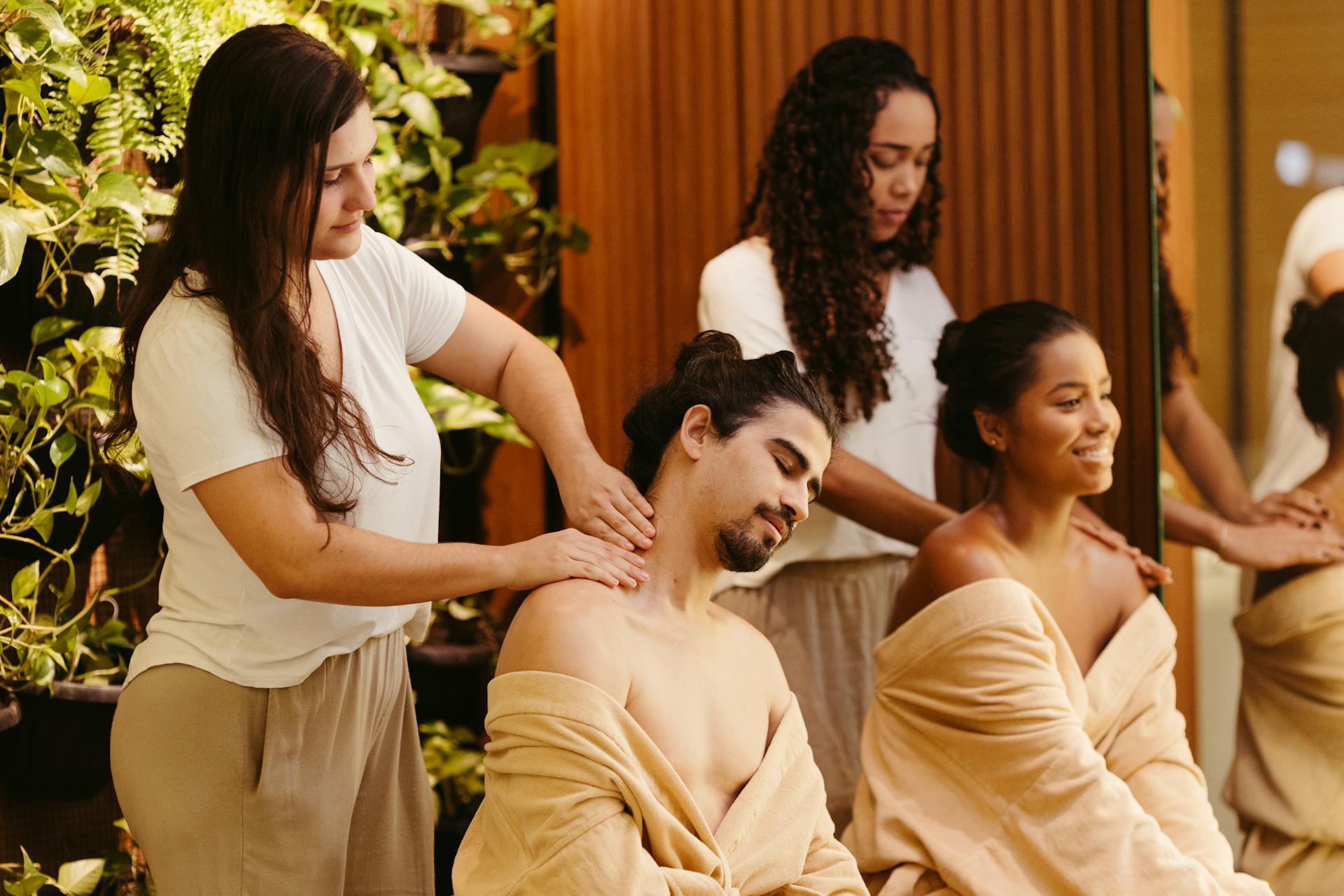 Men and women enjoying relaxing massages at a spa, surrounded by greenery, promoting wellness and relaxation.