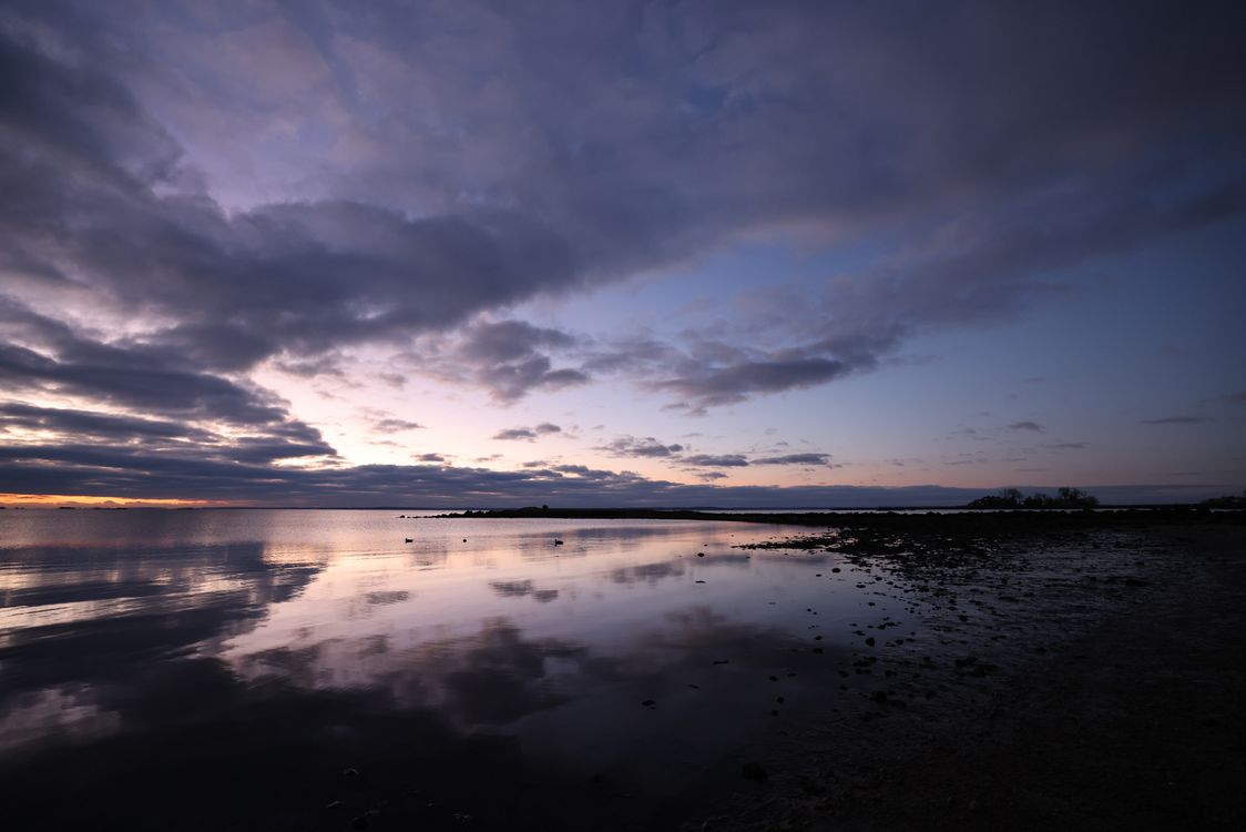 Free Serene sunset at Stamford coast with reflective sea and cloudy sky, creating a tranquil ambiance. Stock Photo