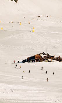 A picturesque alpine ski resort with skiers enjoying a winter sports day on a snowy slope.
