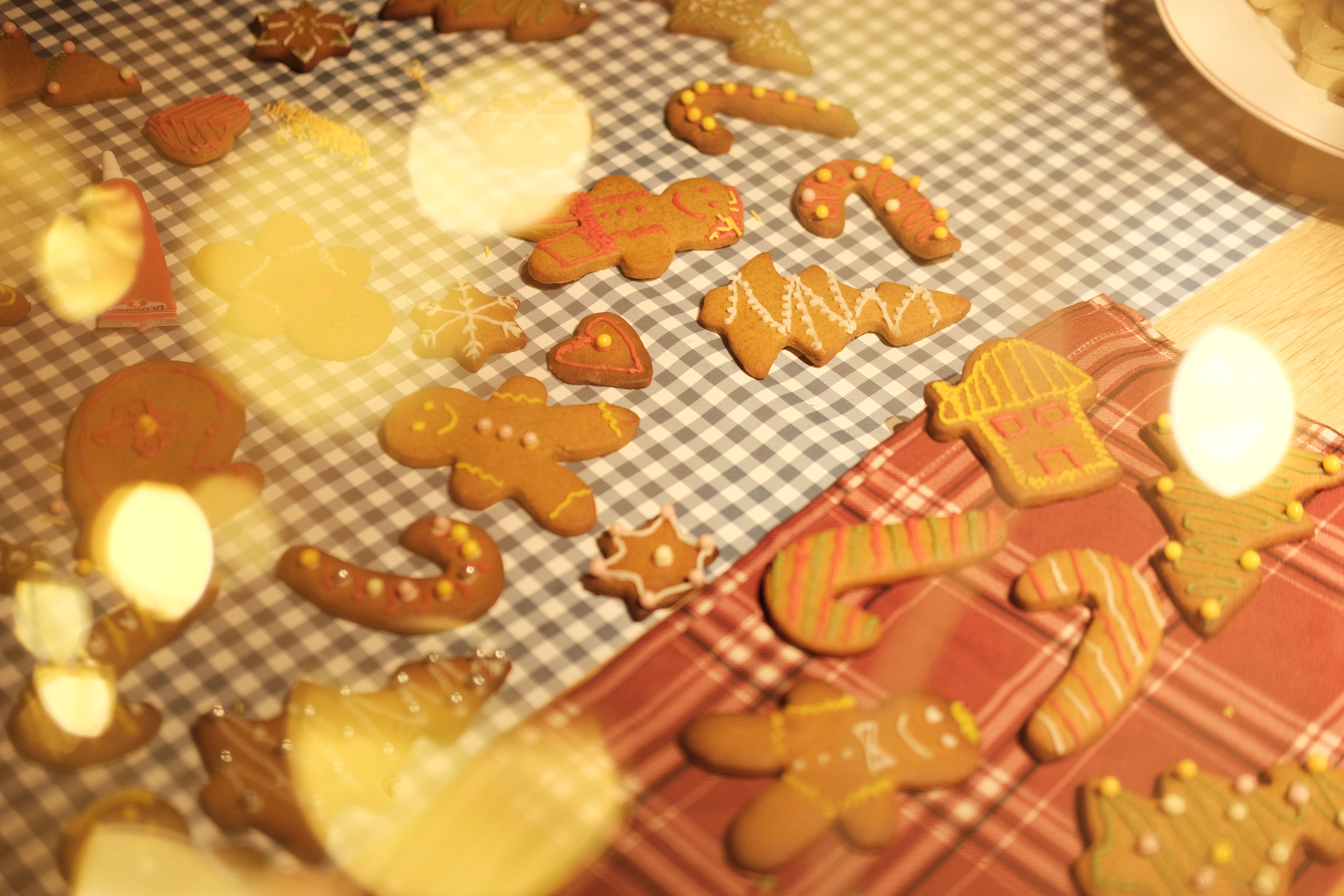 A warm and festive assortment of gingerbread cookies decorated for the holiday season on a checkered cloth.