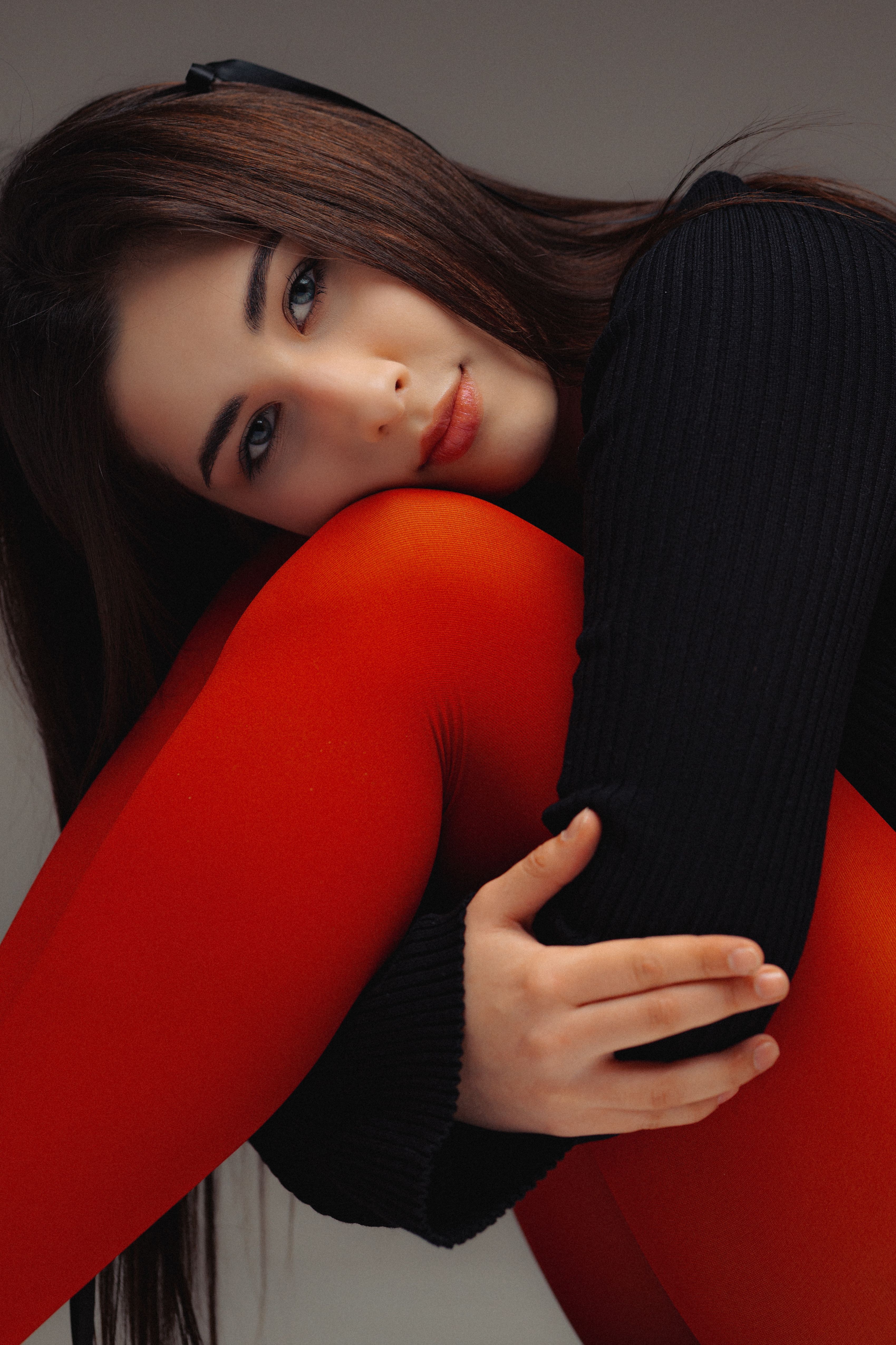 Artistic portrait of a woman in a black top and striking red tights. Studio shot.