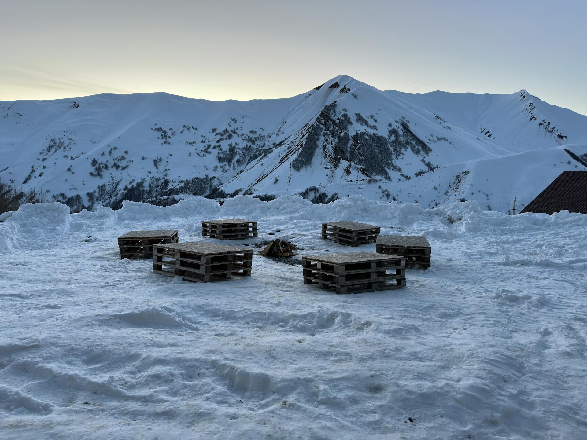 Scenic winter landscape showcasing wooden pallets and snowy mountains in Tbilisi, Georgia.