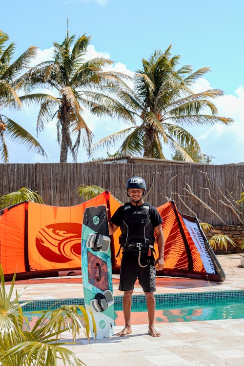 Man in a Helmet Holding a Kitesurfing Board and Smiling 