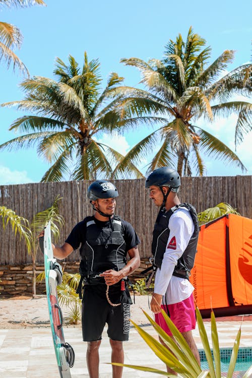 Men in Helmets Holding a Kitesurfing Board