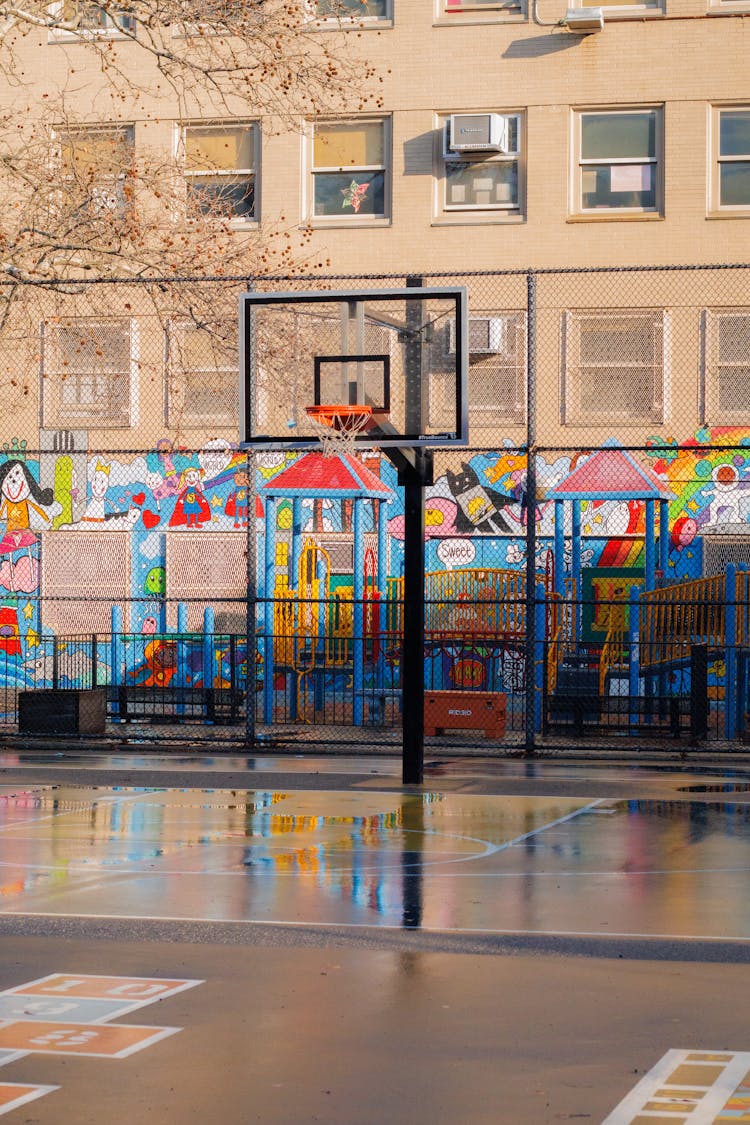 Basketball Court And Playground By School Building