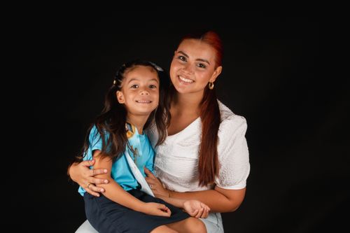 Free A heartwarming portrait of a mother and her daughter smiling together in a studio setting. Stock Photo