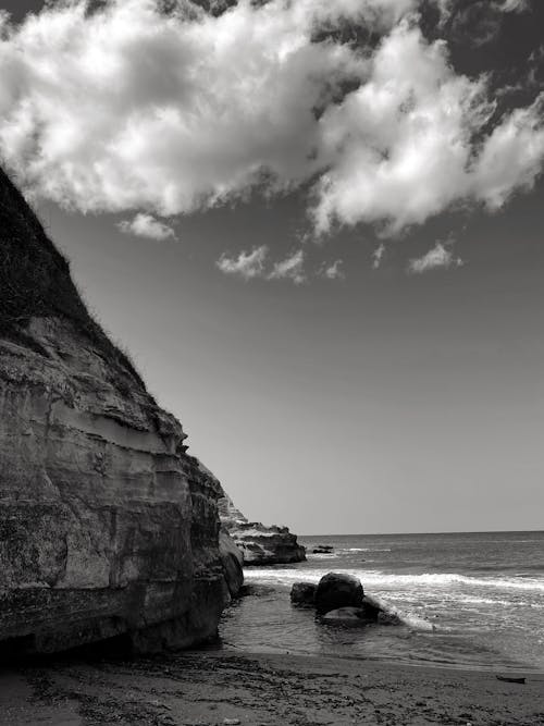 Black and White Photo of a Cliff on the Shore 