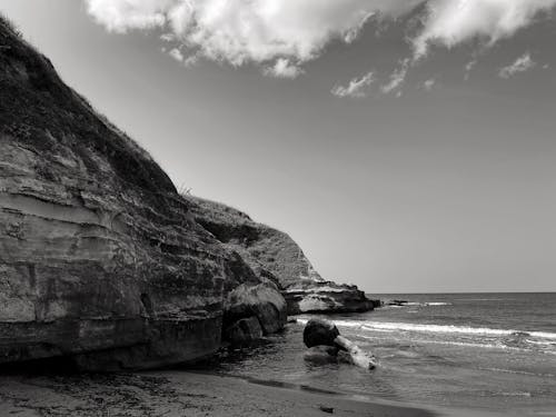 Black and White Photo of a Cliff on the Shore 