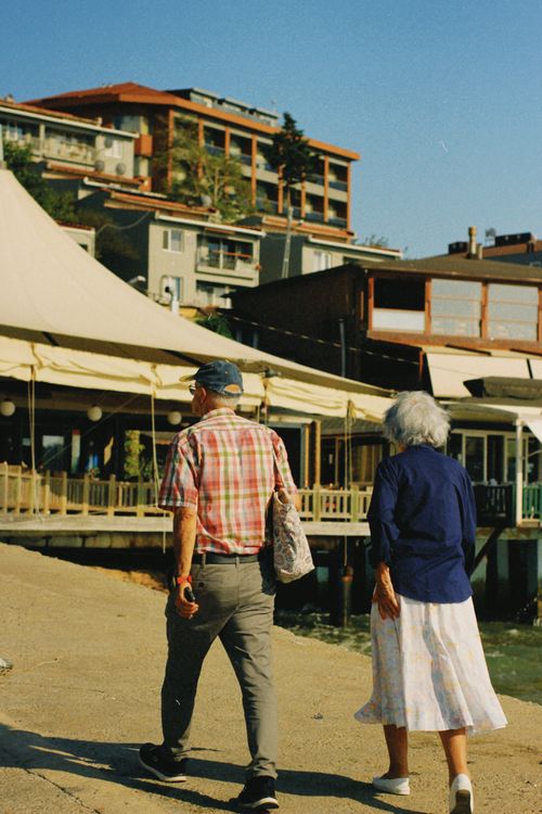Free Senior couple enjoys a leisurely walk near urban waterfront on a sunny day. Stock Photo