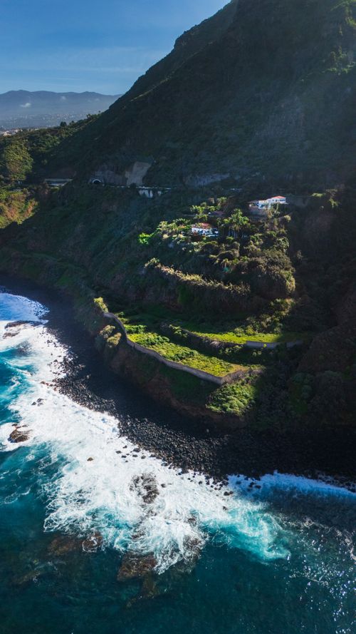 Free Stunning aerial shot of the coastal cliffs and ocean waves at Playa de las Americas, Spain. Stock Photo