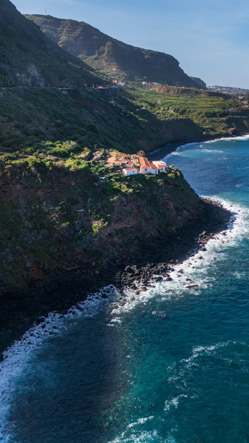 Aerial View of Houses on a Cliff and Waves Crashing on the Shore 