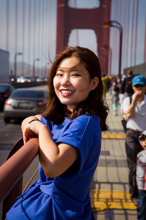 Smiling Woman in Blue Dress on Bridge