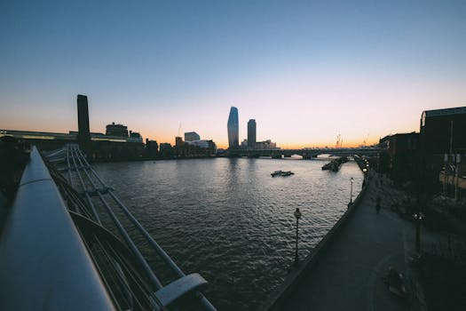 日落时分，城市天际线与河流的壮丽景色中，一座现代桥梁格外引人注目